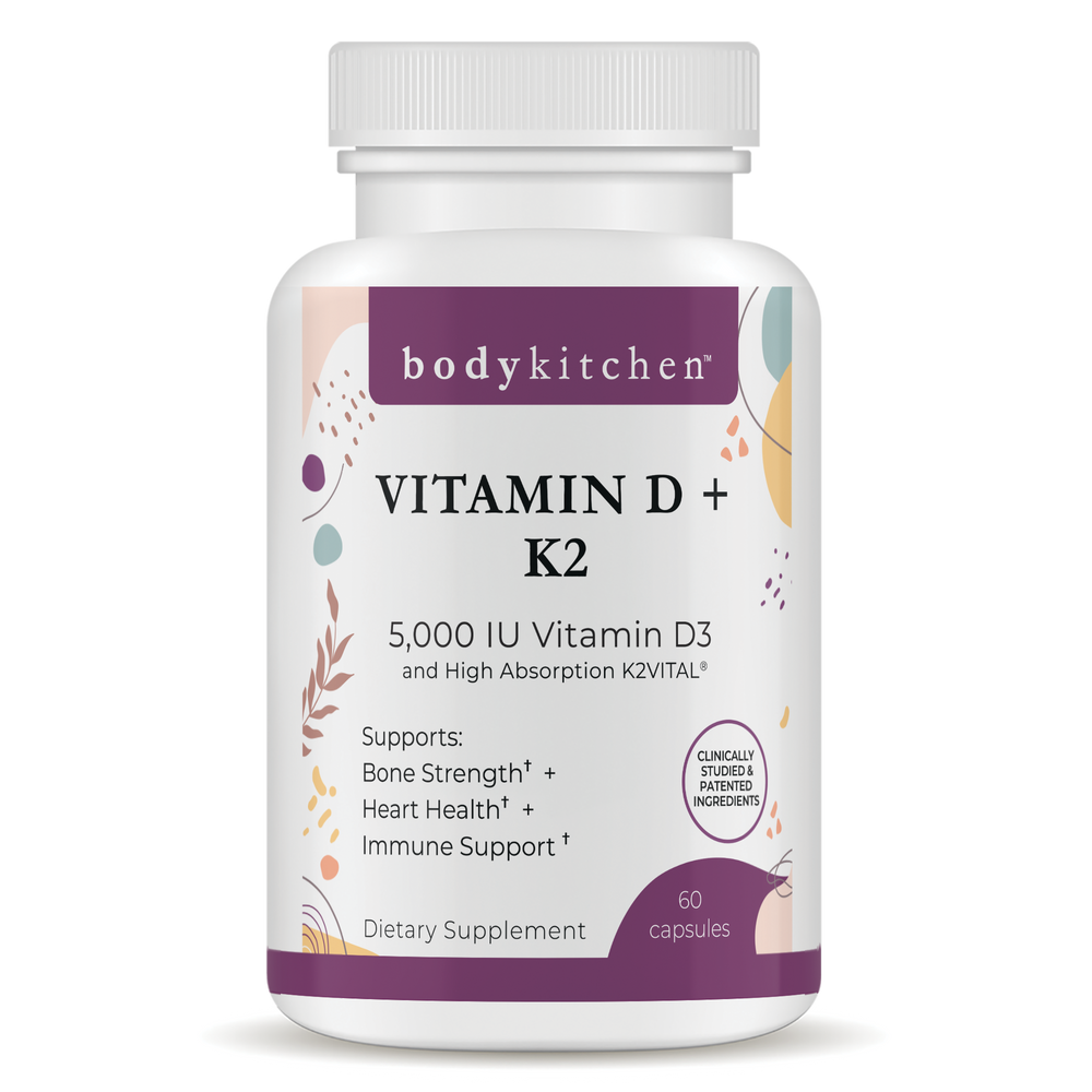 A bottle of Body Kitchen Vitamin D + K2 supplement with 60 capsules, featuring 5000 IU of Vitamin D3 and 180 mcg of K2. The label highlights bone strength, heart health, and immune support.