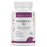 A bottle of Body Kitchen Vitamin D + K2 supplement with 60 capsules, featuring 5000 IU of Vitamin D3 and 180 mcg of K2. The label highlights bone strength, heart health, and immune support.
