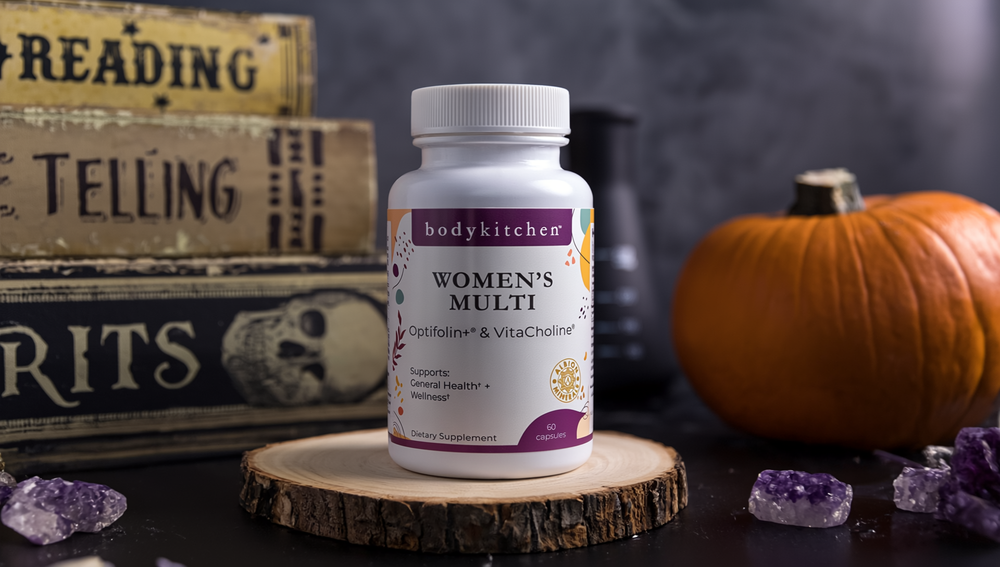 Bodykitchen Women's Multi supplement bottle on a wooden stand with books and a pumpkin in the background